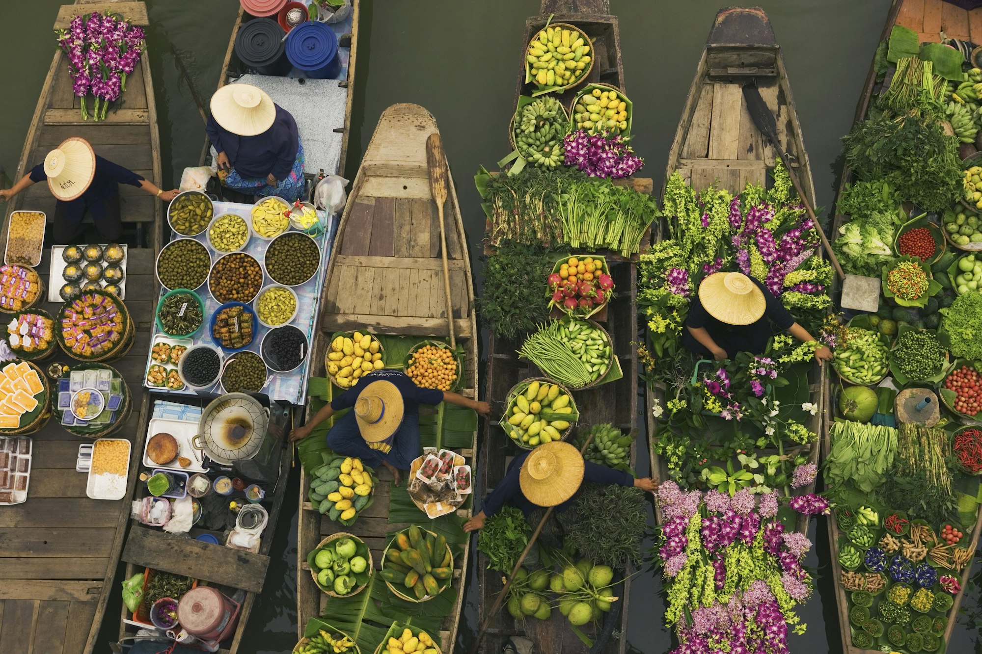 Aerial view of a floating market on a canal in Bangkok, local boats laden with fresh food, moored